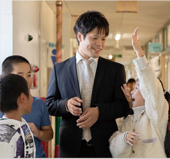 男性の先生と児童たちの画像