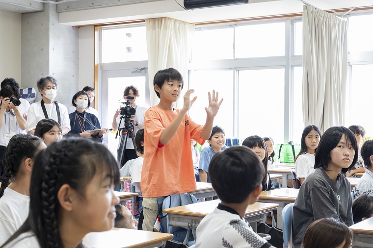 Elementary school children trying to communicate with hand gestures in class