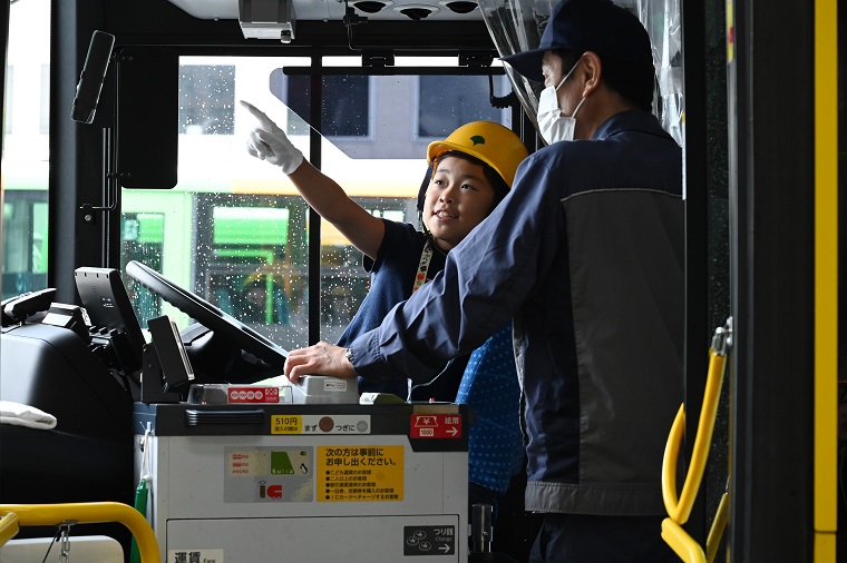 A participant receiving an explanation of on-board equipment while sitting in the driver’s seat