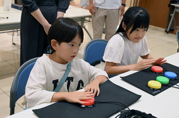 Participants pressing a button-type switch called “Touch-Piko” in the exchange meeting