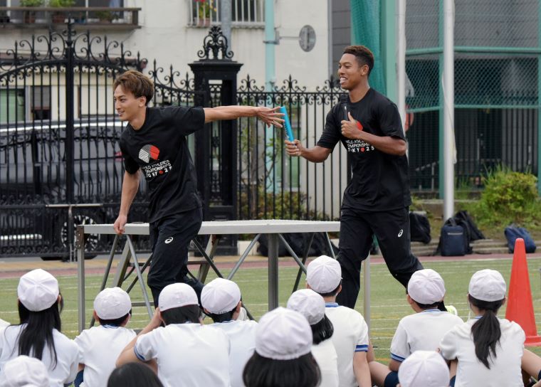 サニブラウン選手と橋岡選手がリレーのバトンを渡す写真