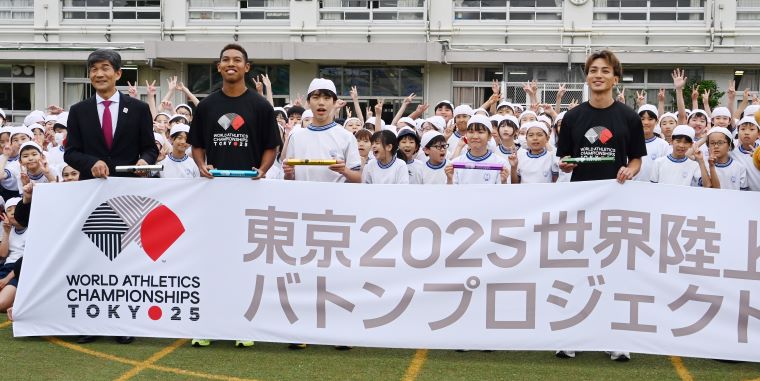 児童たちと選手が校舎の前で記念写真を撮る写真