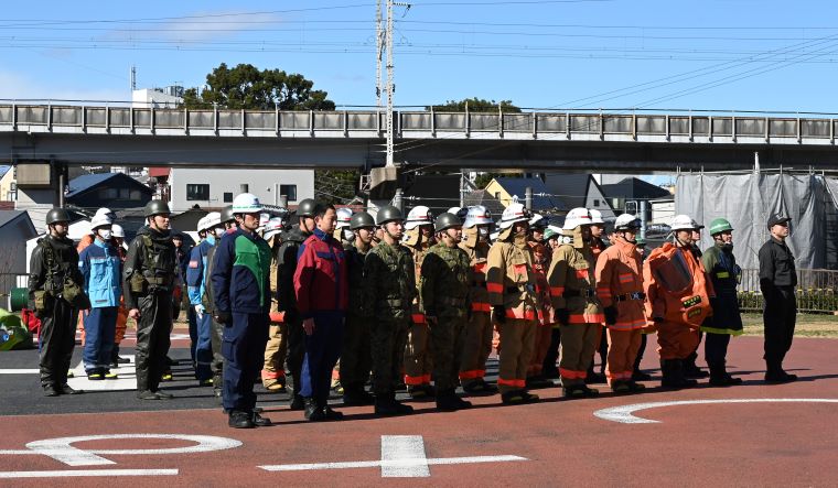 訓練の後、消防、自衛隊、警察などの関係機関が講評を聞く写真
